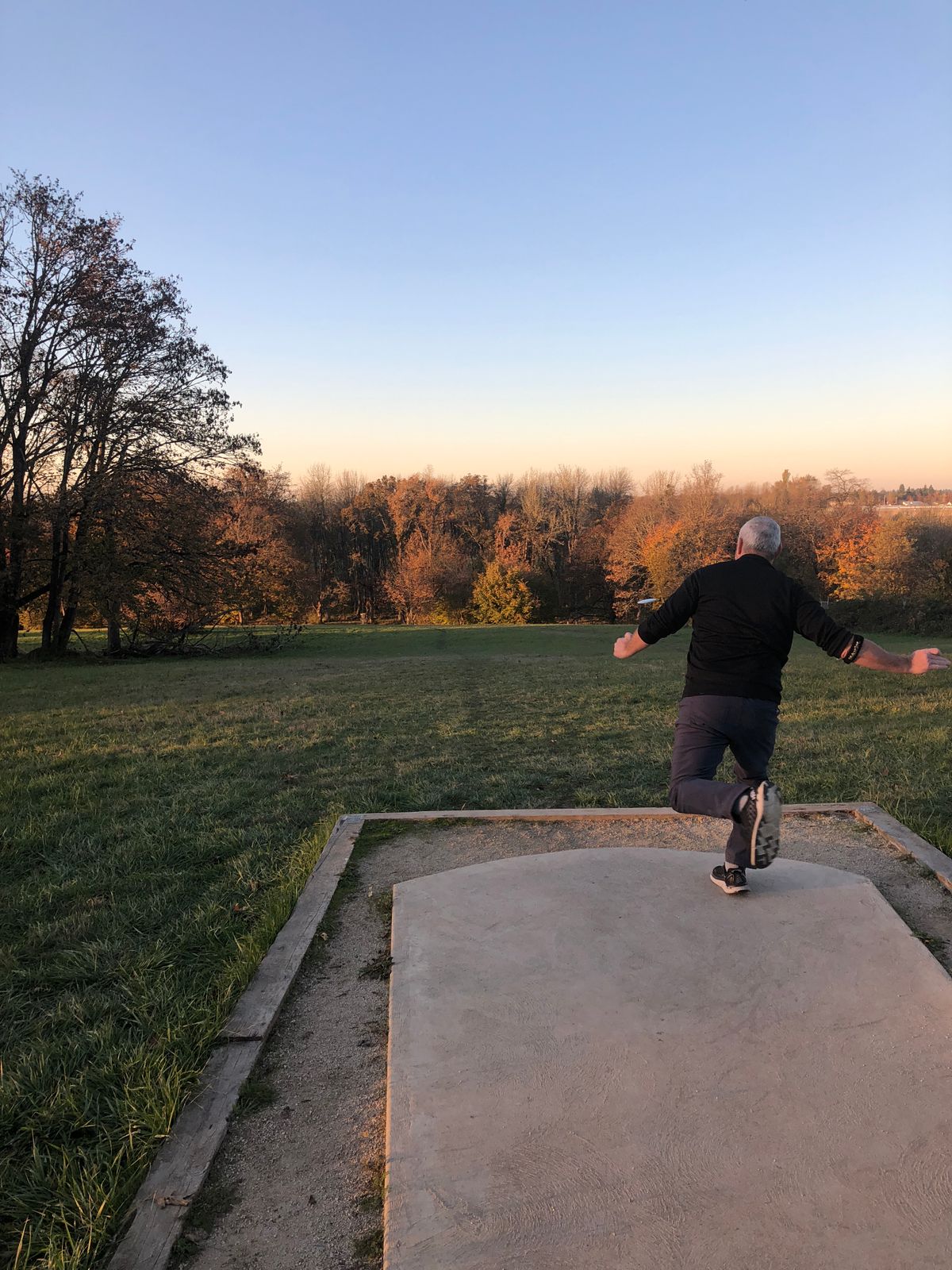 Disc golfer throwing from a concrete tee pad at Stewart Pond in the West Eugene Wetlands