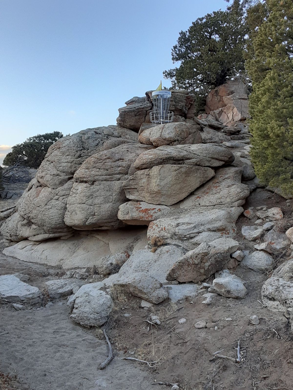 Disc golf basket atop a large boulder formation at Three Peaks